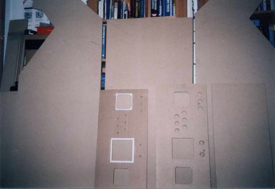 Cardboard prototype piece standing beside the cut wooden parts.